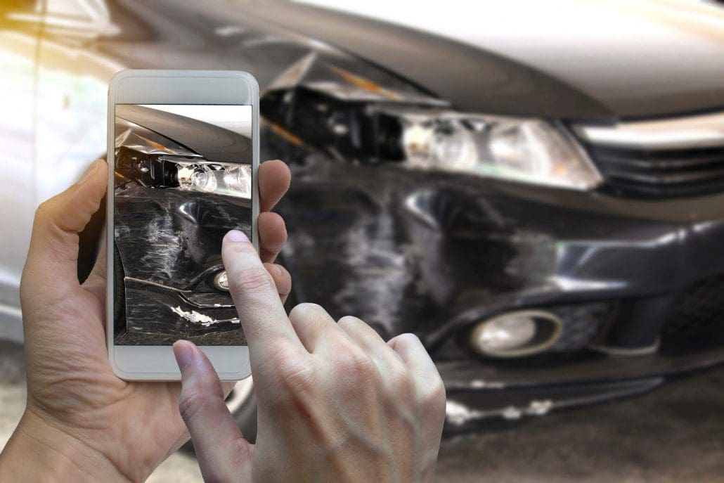 Man takes picture of car accident damage.