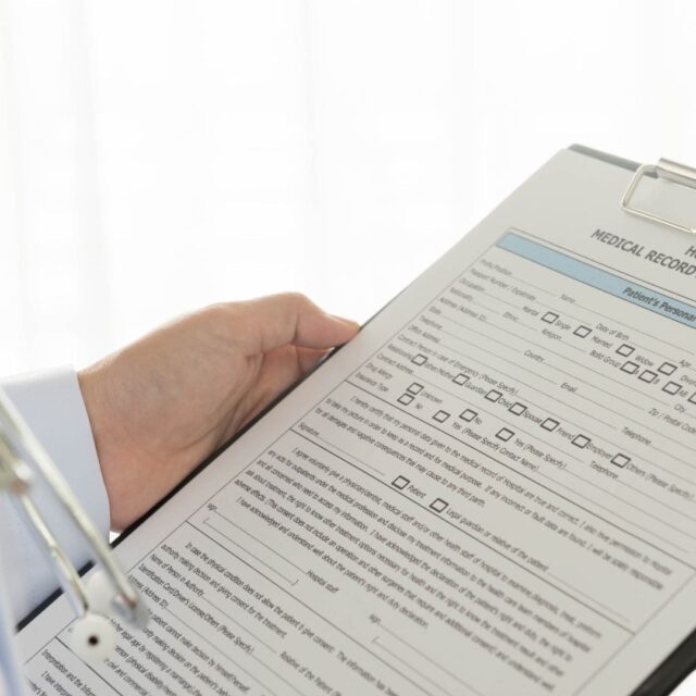 a hand holding a clipboard with medical records